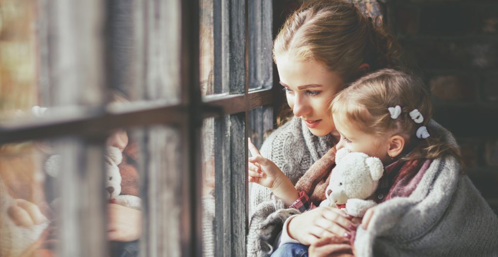 family mother and child daughter look out window on rainy autumn day