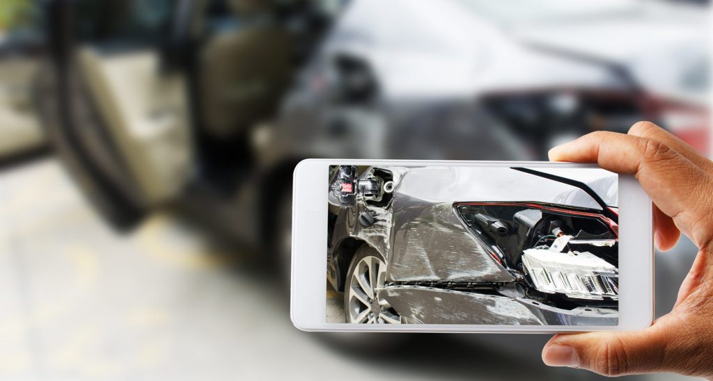Close up hand holding smartphone and view photo of car accident Vehicle Damage