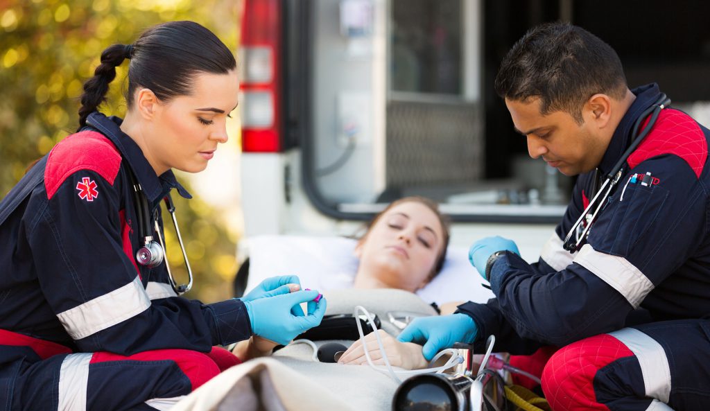 paramedics giving unconscious young woman first aid Injured Motorist