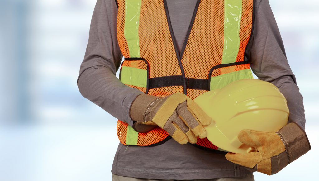 Worker with helmet in orange security vest. Laborer